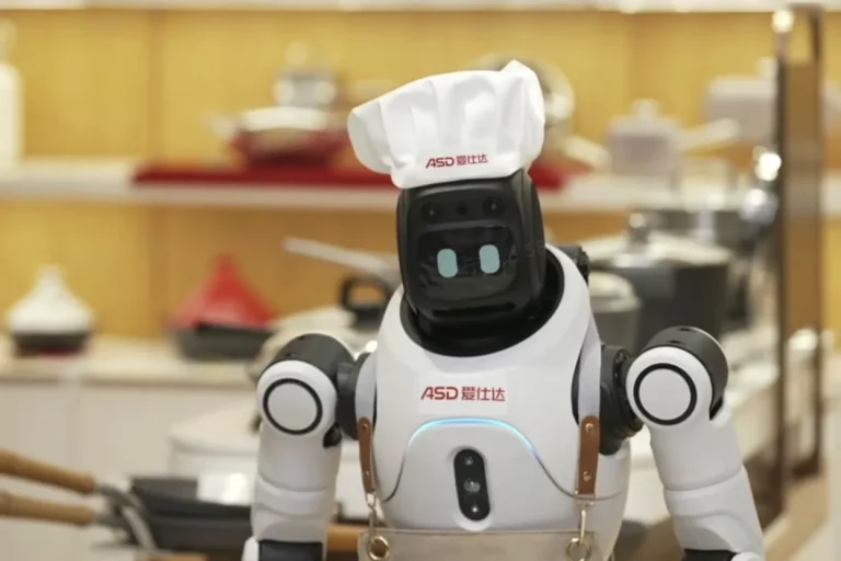 Robot humanoïde X2 d'AGIBOT équipé d'une toque de cuisinier dans un environnement de cuisine avec ustensiles et vaisselle en arrière-plan