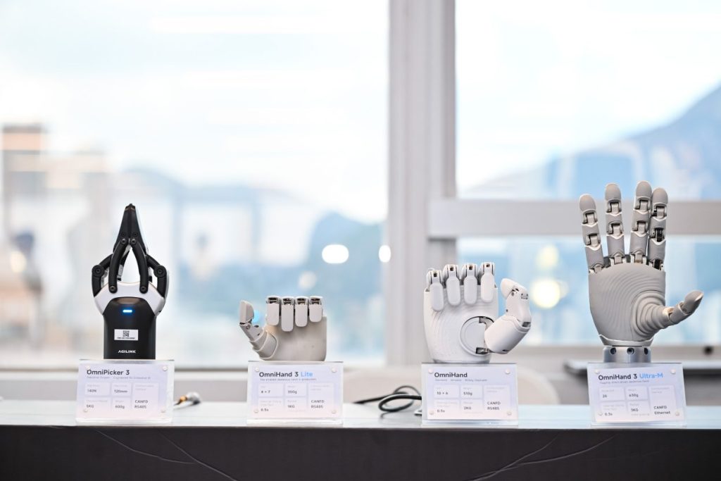 Quatre mains et préhenseurs robotiques exposés sur une table avec des cartons descriptifs