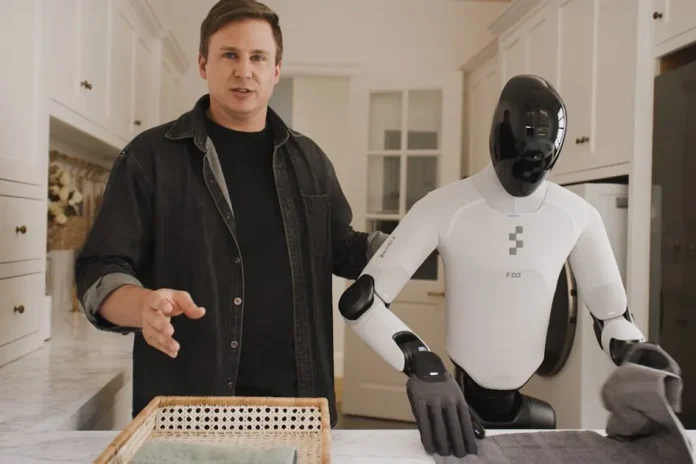 Figure tests Helix 2.5 in 30 unfamiliar homes with no on-site training Person presenting the Figure humanoid robot running the Helix 2.5 model during a demonstration in a home kitchen