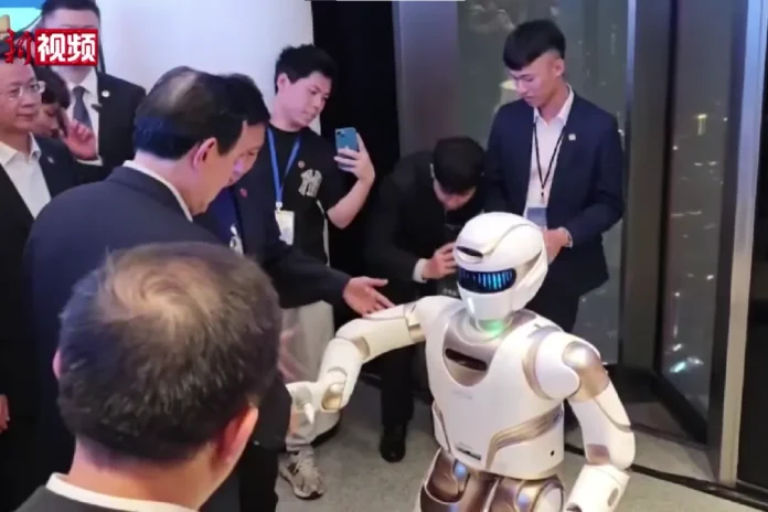 Peau de silicone et 88 articulations : les robots humanoïdes d'UBTech arrivent à partir de 15 500 euros Un robot humanoïde à coque blanche et écran facial lumineux présenté devant un groupe de visiteurs portant badges et tenues formelles