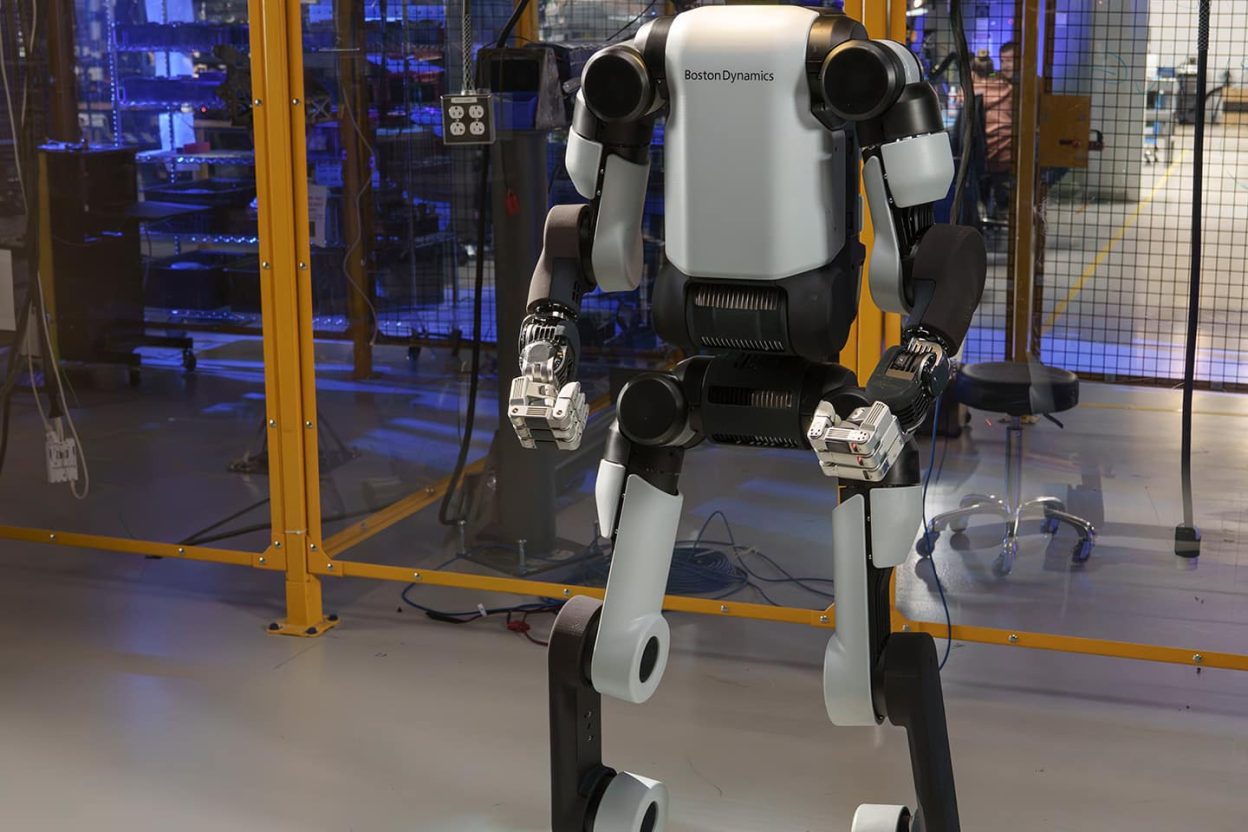 Humanoider Roboter Atlas von Boston Dynamics mit Markenlogo auf dem Rumpf in einer abgetrennten Industrieumgebung