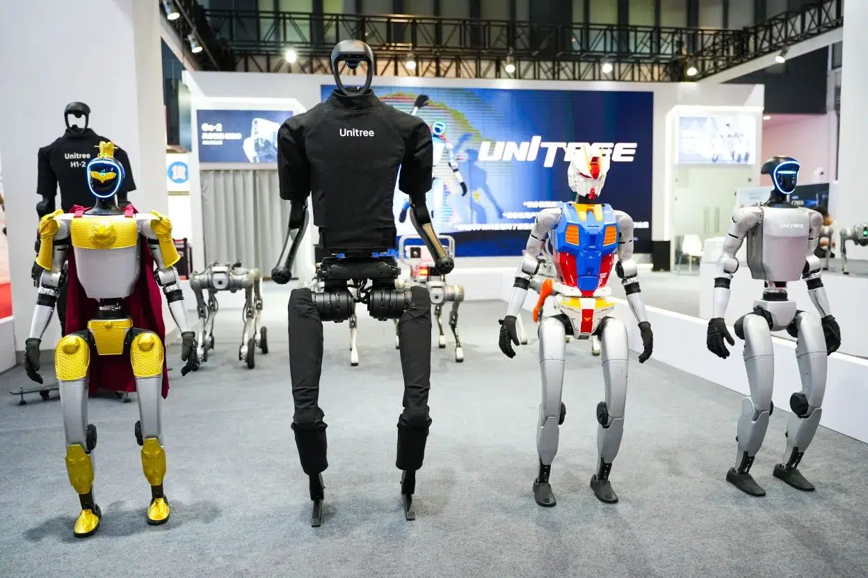 Quatre robots humanoïdes alignés sur un stand portant le logo Unitree, lors d'une démonstration en salon