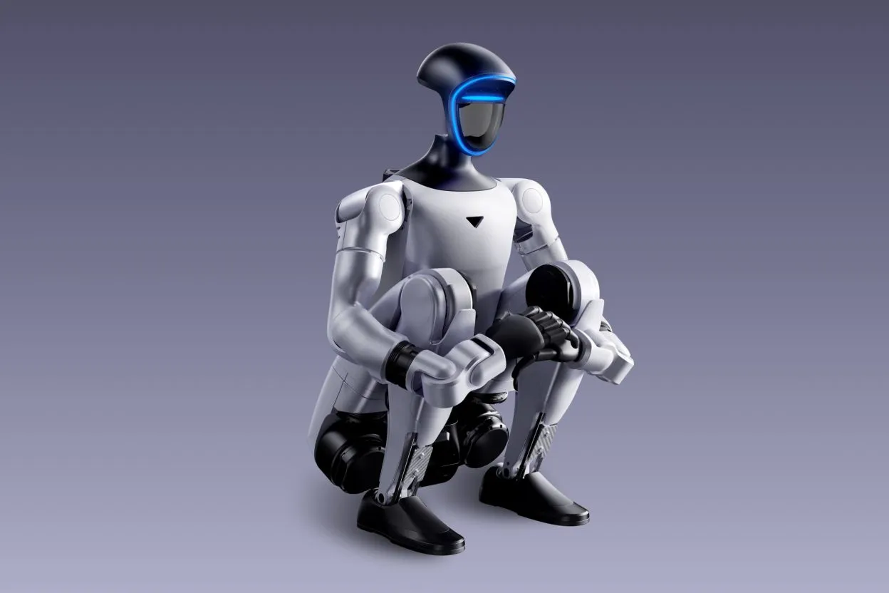 White bipedal humanoid robot with a black helmet and a glowing blue strip, crouching and holding a helmet in its hands