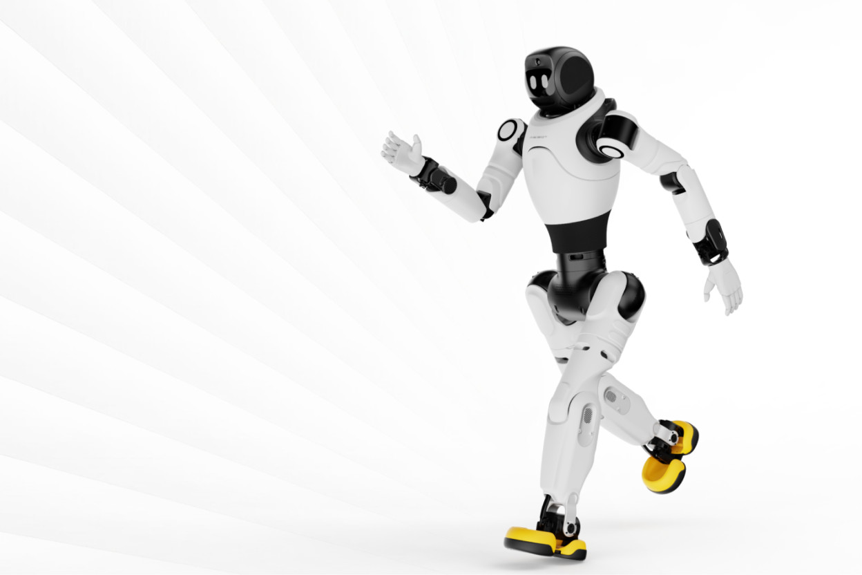 Robot humanoïde blanc et noir en position dynamique sur une jambe, bras levés, chaussures jaunes.