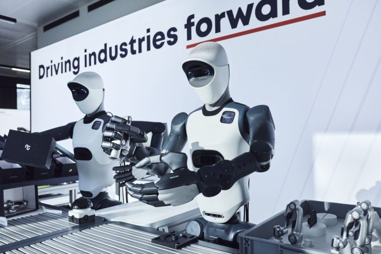 Bras robotique industriel jaune manipulant une pièce métallique dans un atelier