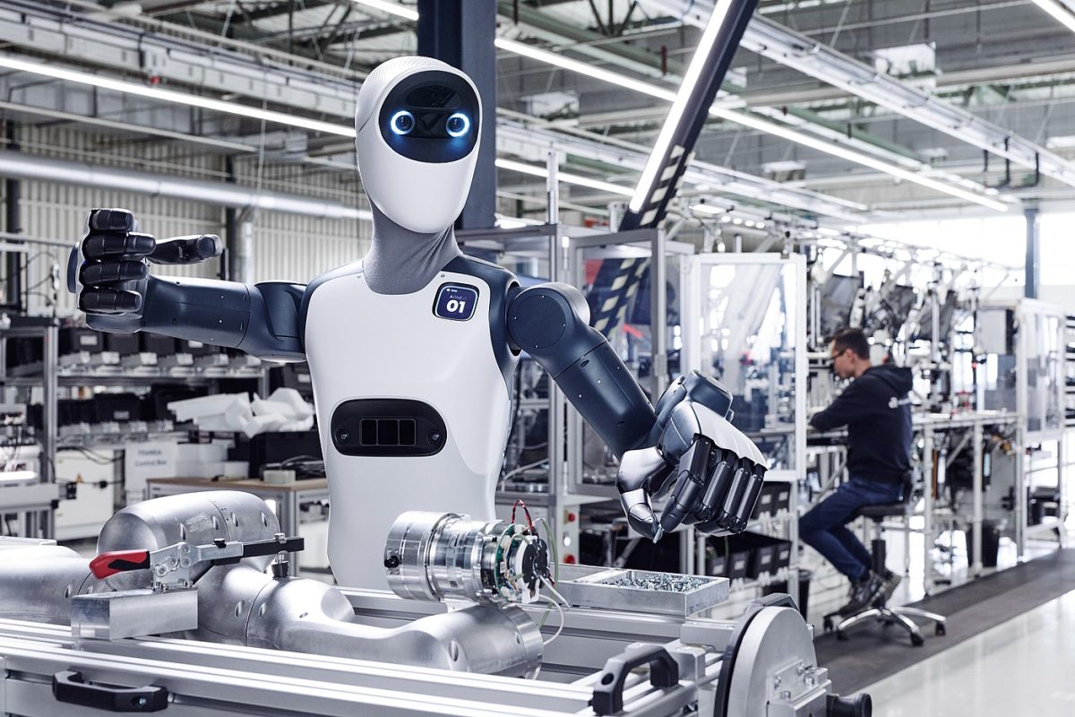 Robot humanoïde blanc debout dans un environnement industriel aux côtés d'un opérateur